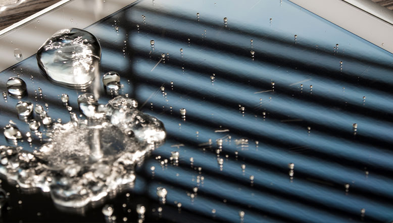 Gota de agua cayendo en el móvil de una mesa de tu hogar